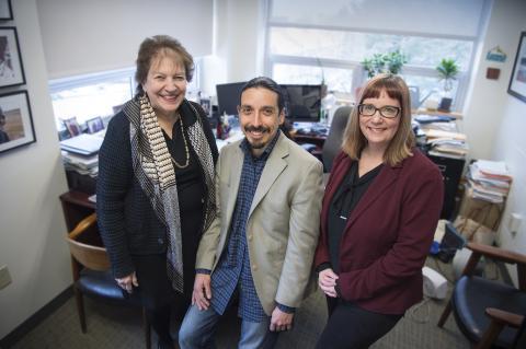 Three professors posing for photo standing by a desk